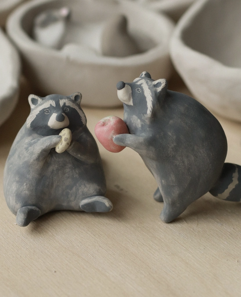 Two Gray Clay Raccoons with Apple and Cookie