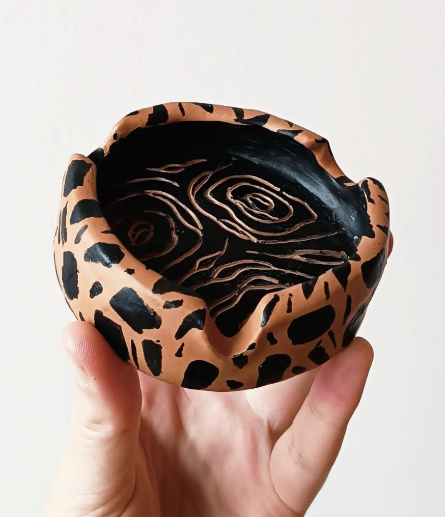 Glossy Black Ashtray with Red “X-Eyed” Clay Figure